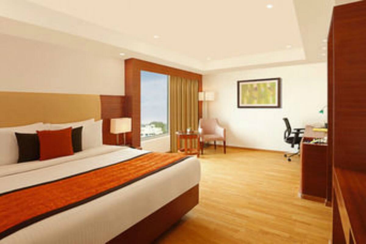 Habitación de hotel con una cama grande, un escritorio, una silla y una ventana con cortinas.