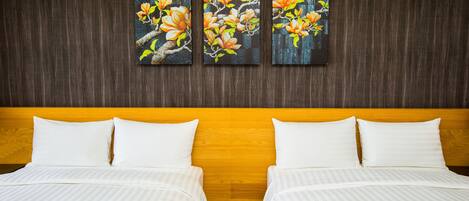 A hotel room with two beds, a wooden headboard, and a wall-mounted floral artwork.