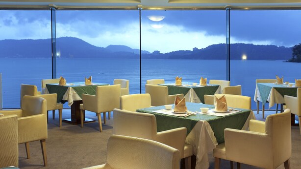 A restaurant with tables set for dining, overlooking a body of water and hills. - Lealea Garden Hotels - Sun Lake (Yuchi)