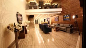 Eine großzügige Lobby mit glänzendem Holzboden, einer Rezeption und einer Sitzecke mit Sofas und Sesseln.