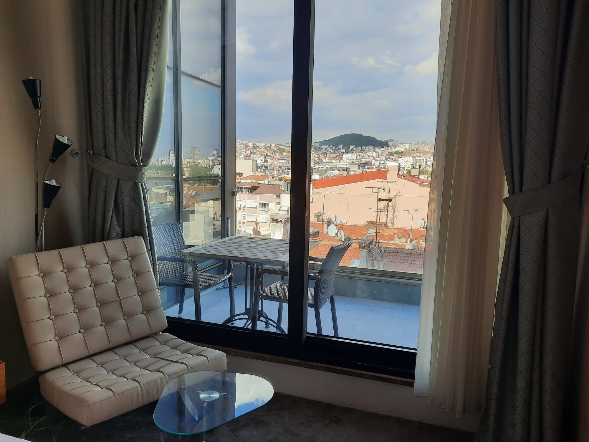 Ein modernes Wohnzimmer mit einer Couch, einem Glastisch und Blick auf eine Skyline durch große Fenster.
