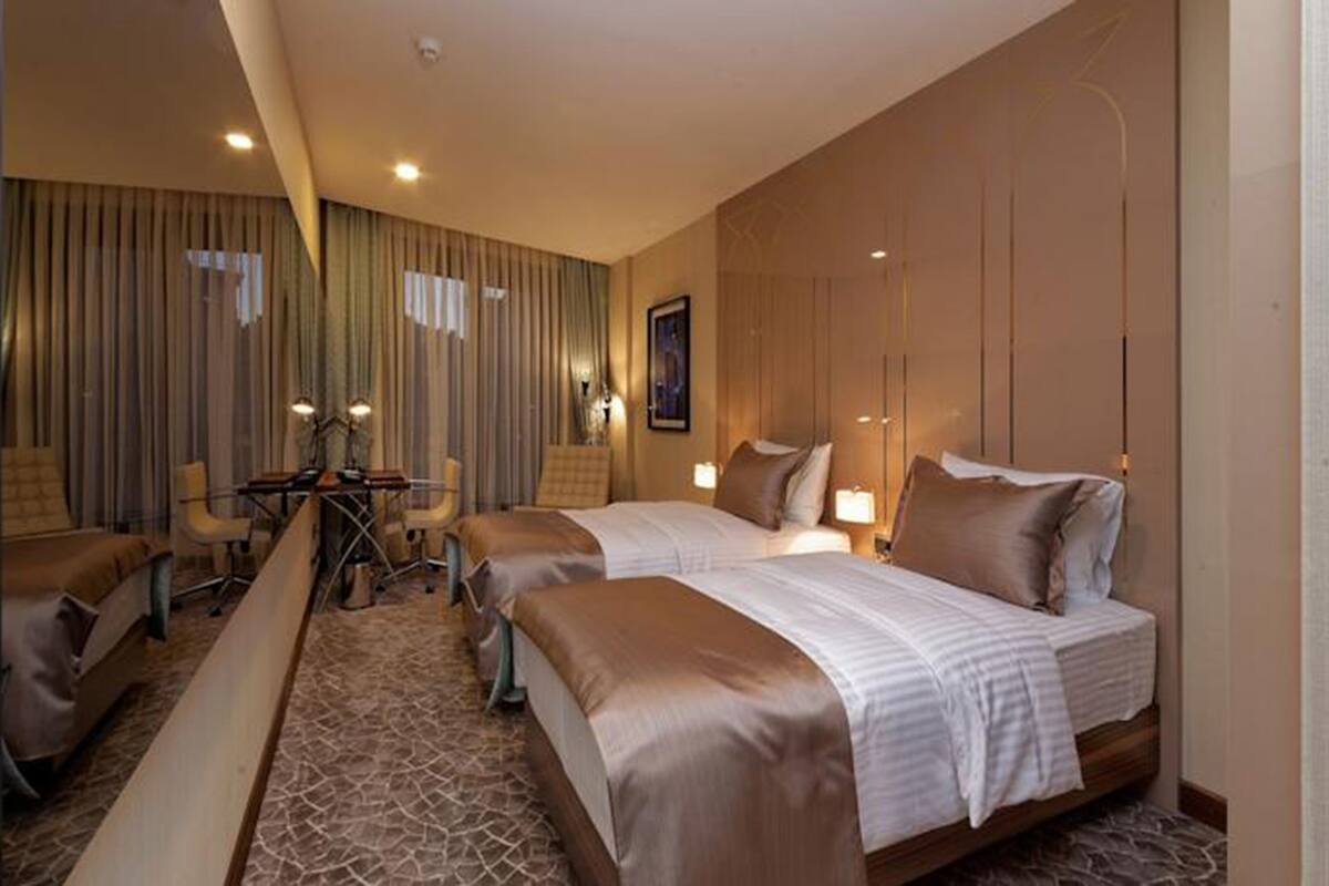 A hotel room with two beds, a desk, and a chair.