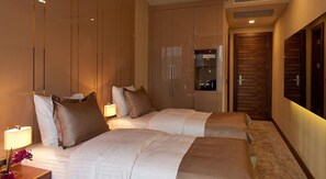 A hotel room with two beds, a wardrobe, and a mirror.