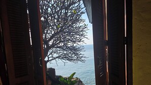 Une vue à travers une porte ouverte, avec un arbre et une côte rocheuse en arrière-plan.