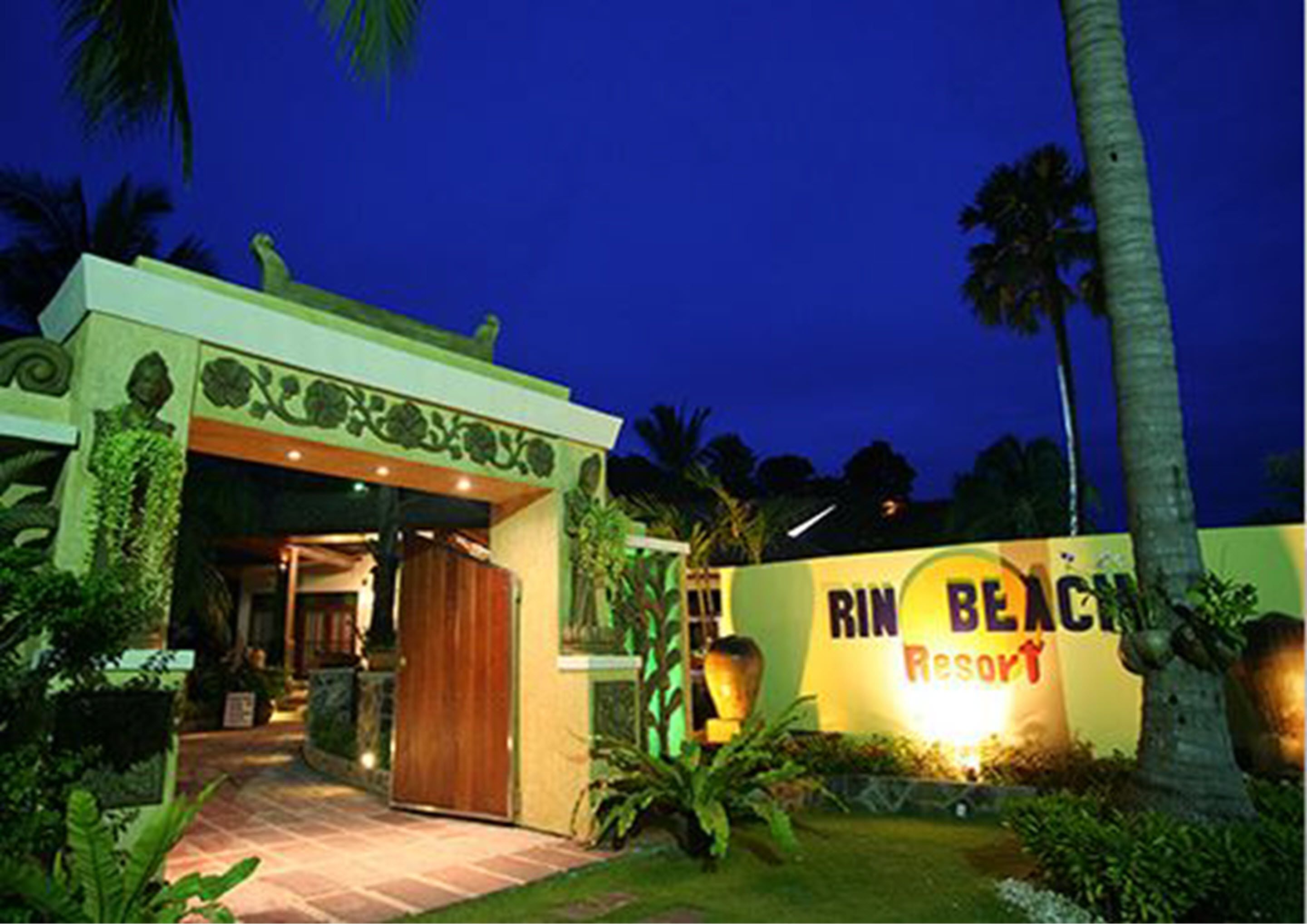 Entrada a un resort con un letrero que dice "Rin Beach Resort" y un camino que lleva a la puerta.