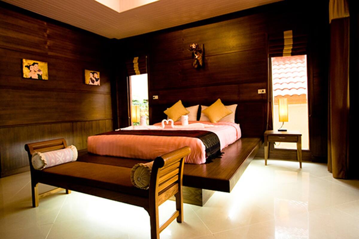 A bedroom with a bed, bedside tables, and a wooden headboard.