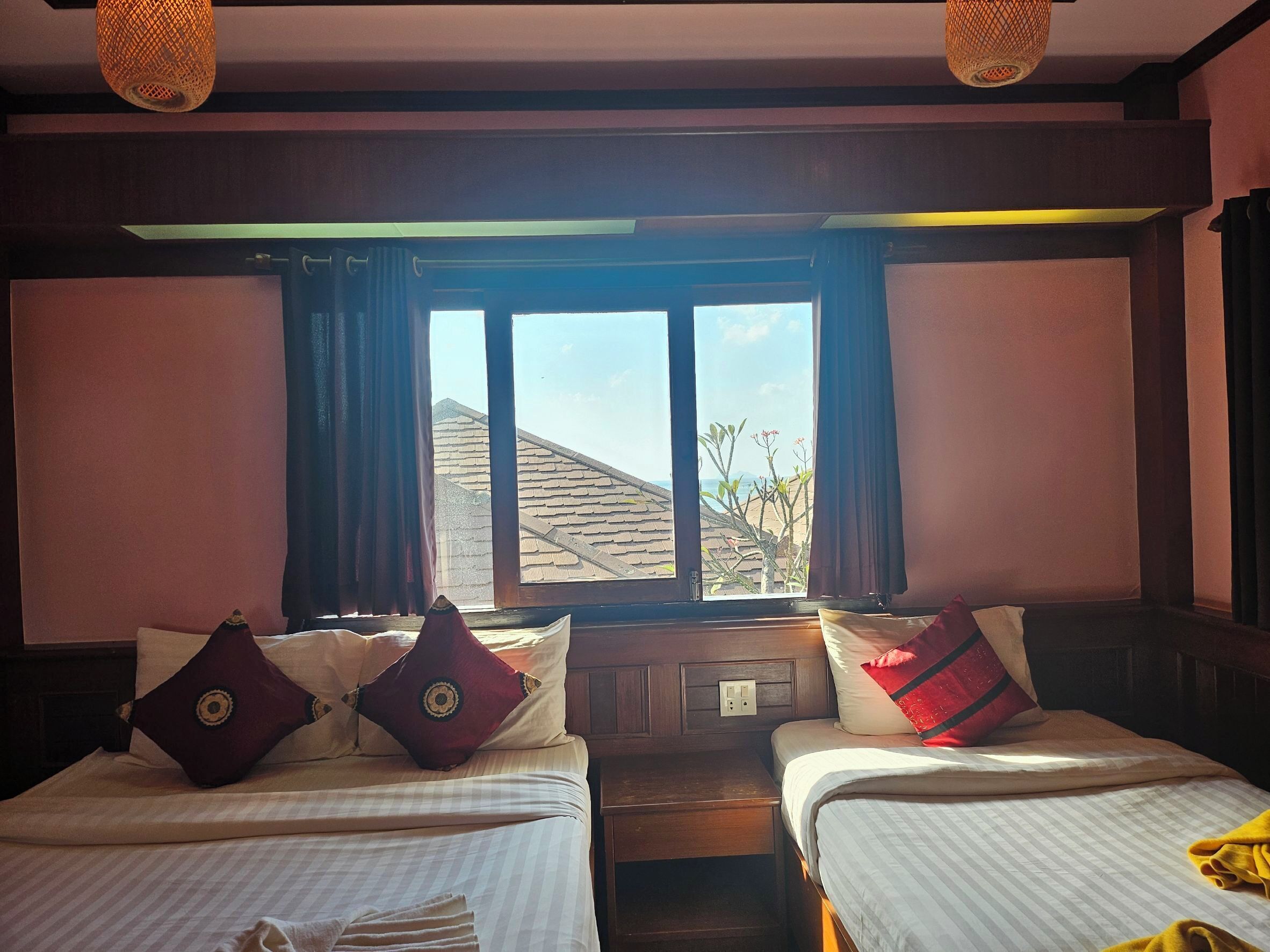 Habitació amb dos llits, una finestra amb cortines i un sostre de fusta.