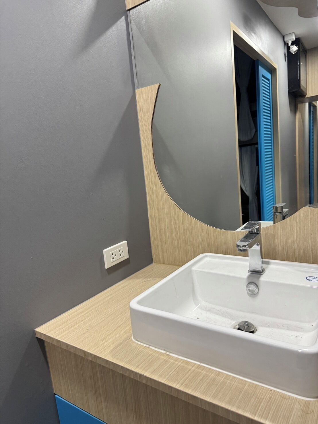 A bathroom with a white sink, a mirror, and a wooden vanity.