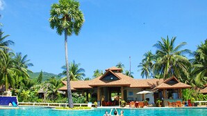 Un complexe hôtelier doté d’une piscine, de palmiers et de chaises de plage.