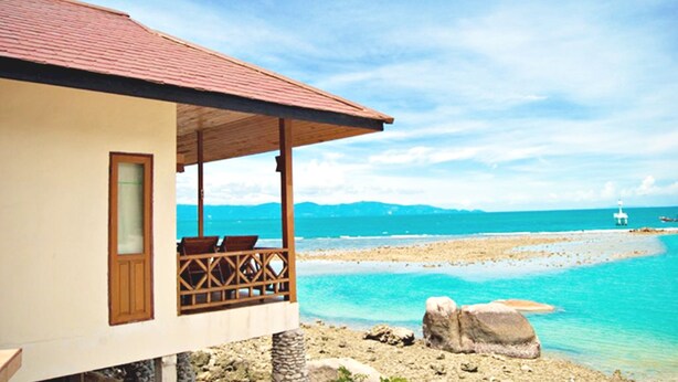 Une propriété située en bord de mer, dotée d’un patio couvert, offrant une vue sur la mer et un aperçu d’un phare situé au loin.