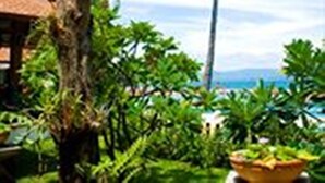 Un complexe hôtelier tropical doté d’un grand arbre, d’un palmier et d’une végétation luxuriante.