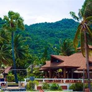 A resort with a pool, palm trees, and a mountainous backdrop.