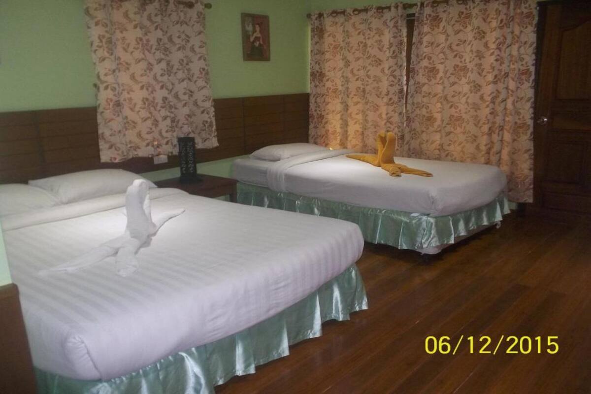 A hotel room with two beds, floral curtains, and a wooden floor.