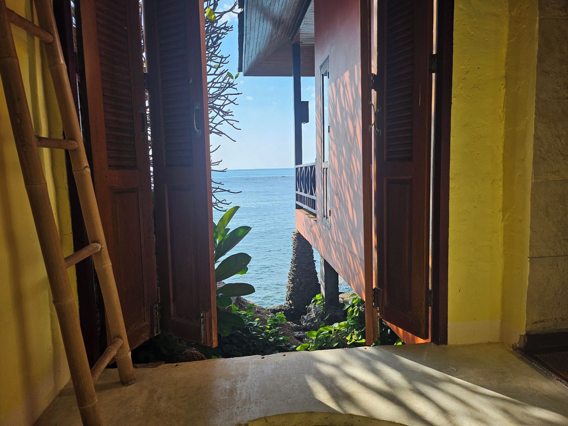 Una puerta que da a un balcón con vista al mar.