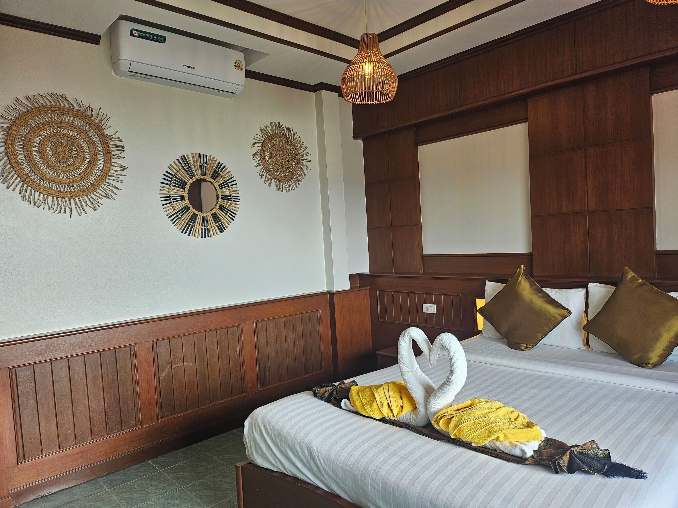 Une chambre d’hôtel avec un lit, des œuvres d’art décoratives au mur, une tête de lit en bois et un luminaire suspendu.