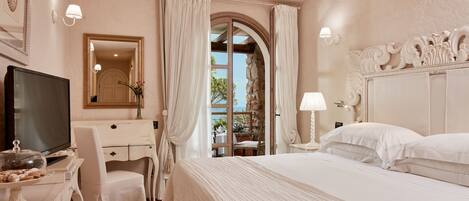 A hotel room with a bed, a desk with a television, a chair, and a mirror.