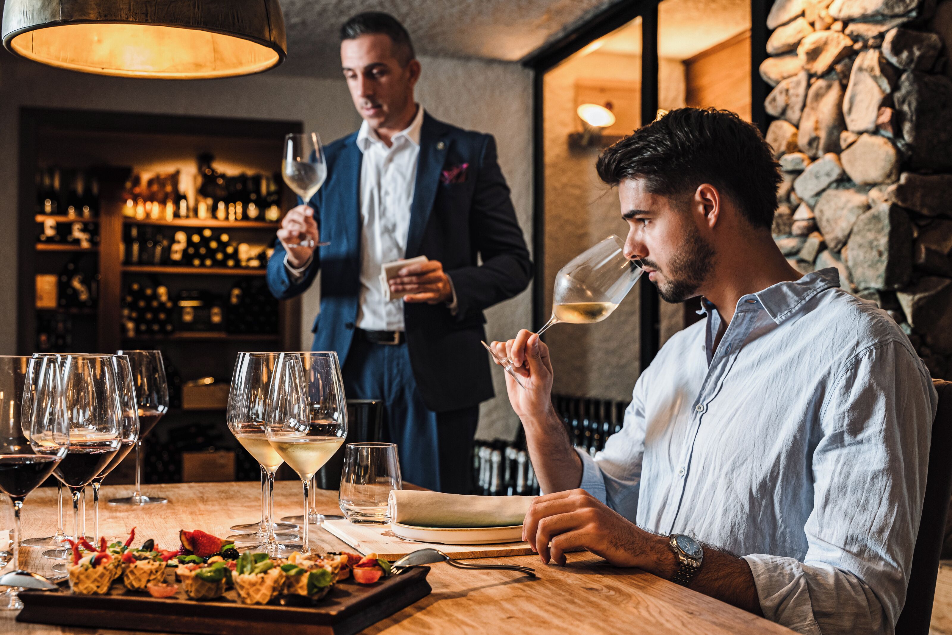 A restaurant interior with a bar area, wine glasses, and a table with food.