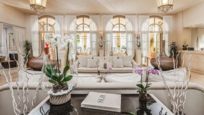 A well-lit living room with a sofa, decorative vases, and a book titled 'Small Luxury Hotels of the World.'