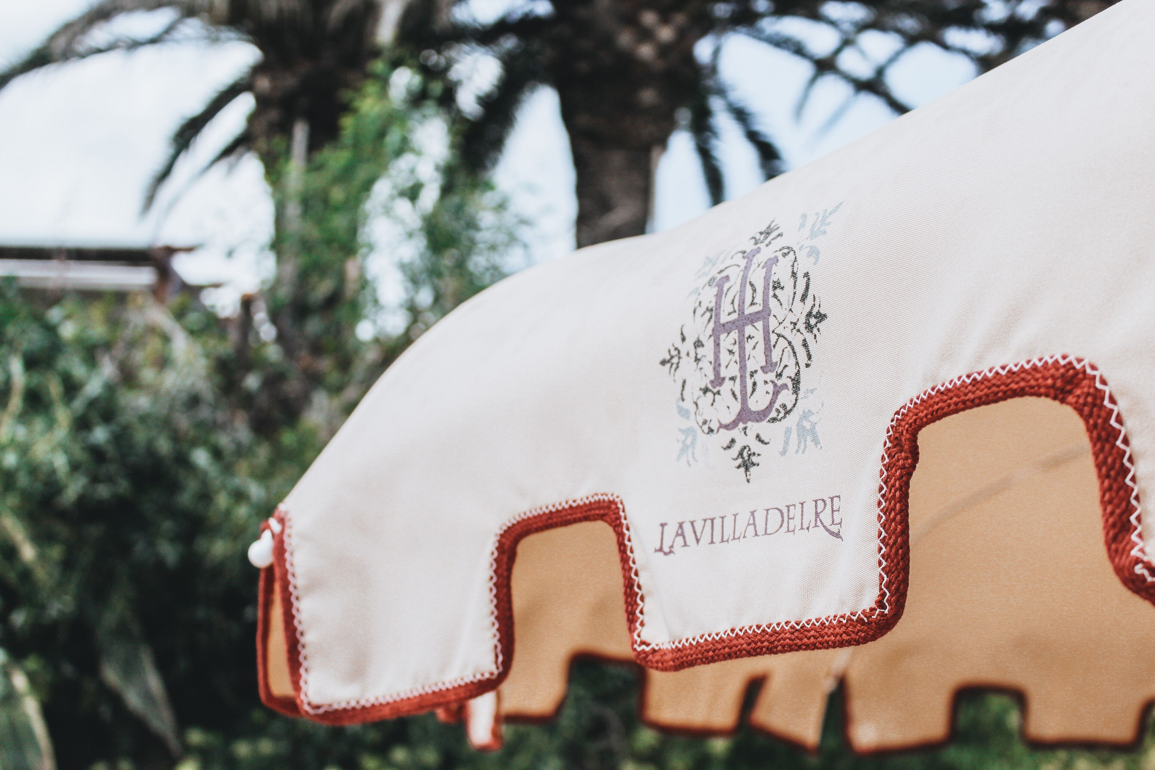 A white cloth with embroidered text and a logo, featuring a red trim.