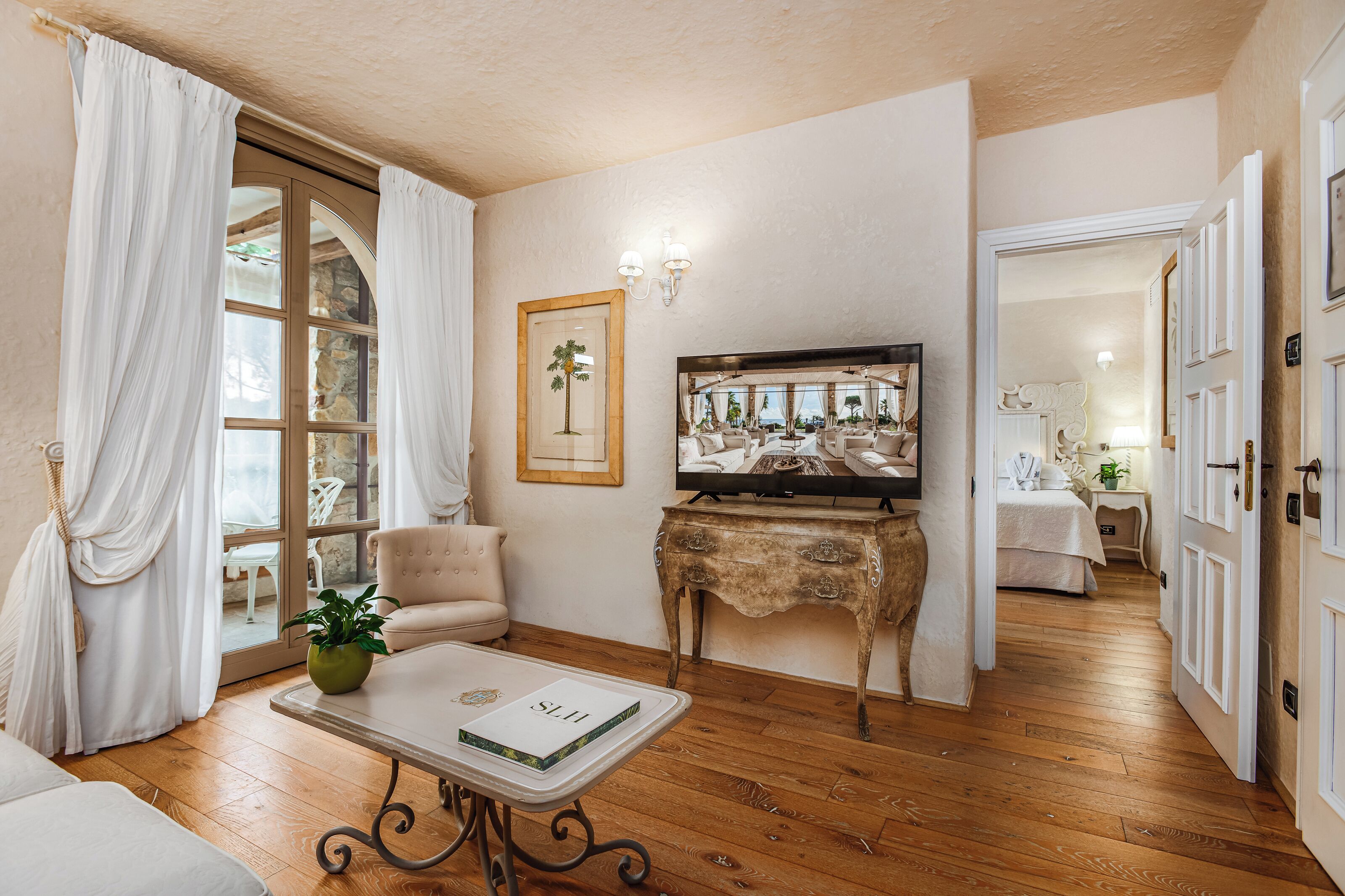 A room with a wooden floor, a sofa, a coffee table with a book, a television, and a framed picture on the wall.