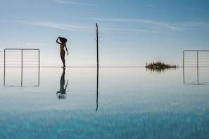 A person standing by a calm body of water with a clear sky.