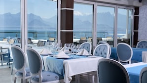 Comedor con mesas dispuestas para una comida, con vistas a una pintoresca vista de la montaña.