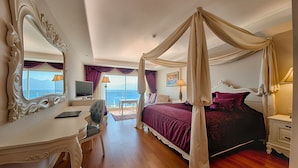 Un dormitorio con cama con dosel, tocador con espejo, escritorio y vista al mar.