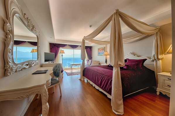 Un dormitorio con cama con dosel, tocador con espejo, escritorio y vista al mar.