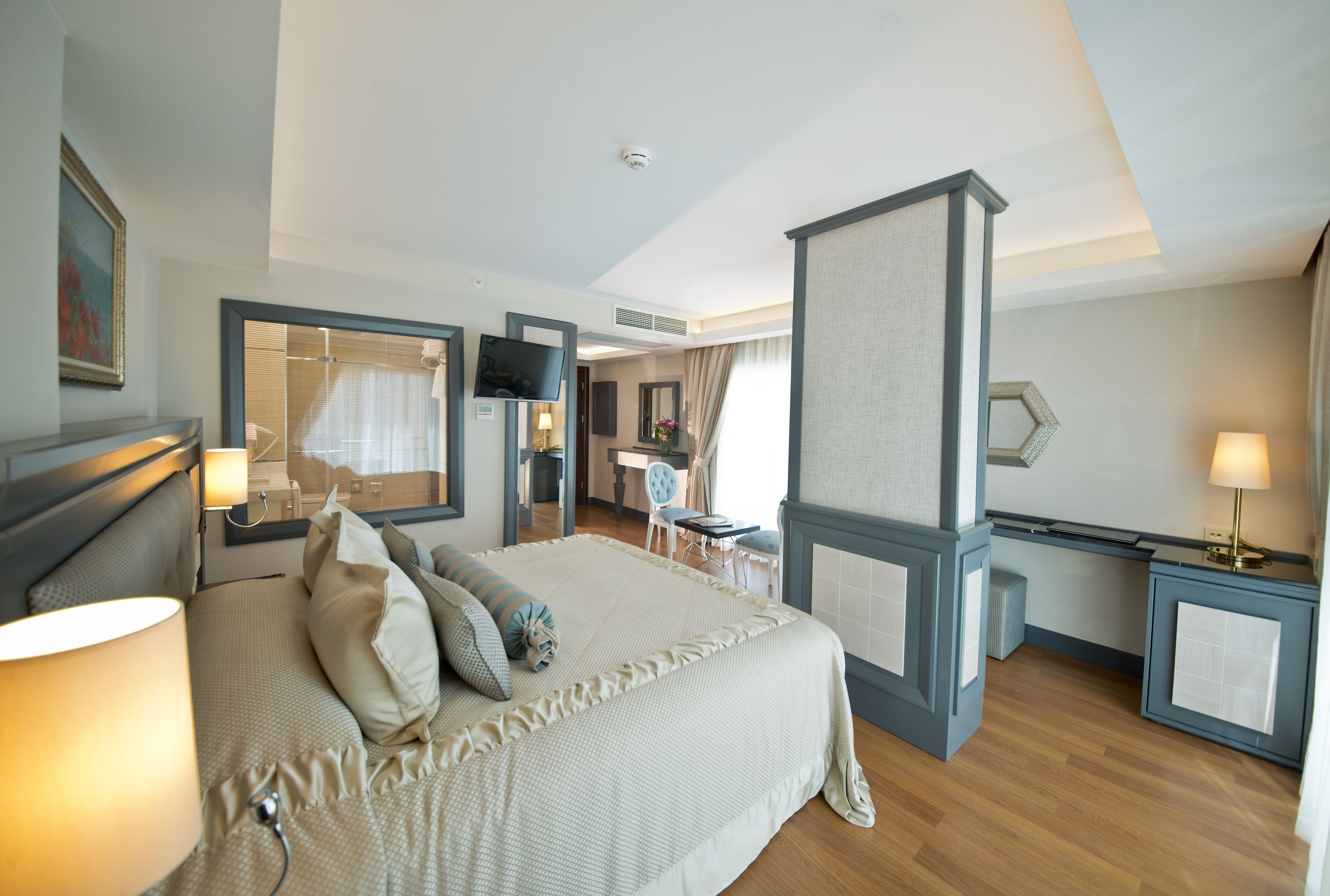 A hotel room with a large bed, bedside tables, a desk, and a shower area.