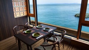 A dining area with a table set for four, large windows with a view of the sea, and a wooden partition with a lattice design.