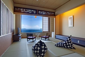 A tatami mat room with a view of the sea, two chairs, a small table, and a pillow. - Hanagoyomi (Sumoto)
