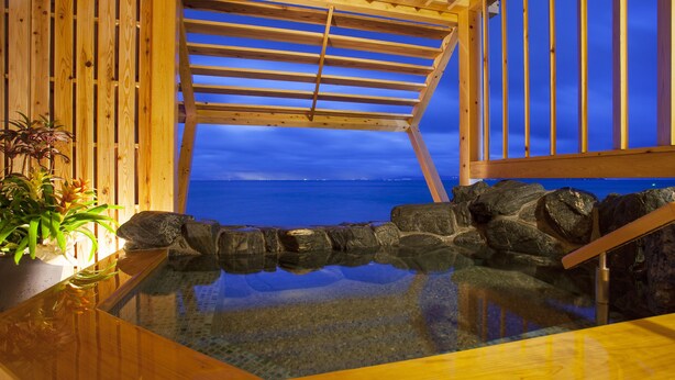 A wooden spa area with a glass floor, wooden beams, and a view of the ocean.
