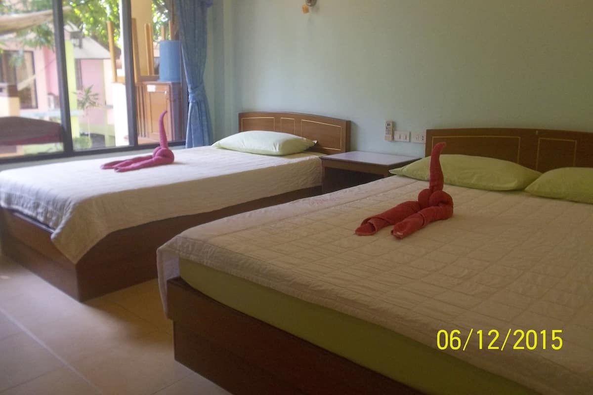 Two single beds with wooden headboards, a small table, and a wall-mounted light fixture.