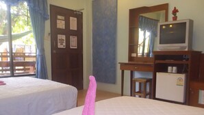 Une chambre d’hôtel avec deux lits, un bureau avec une télévision, un petit réfrigérateur et une fenêtre avec des rideaux.