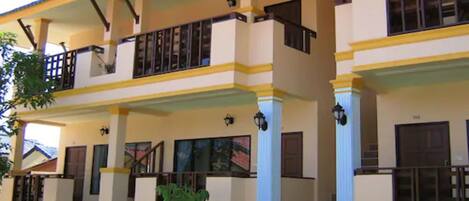 A two-story building with a balcony, large windows, and a staircase leading to the entrance.