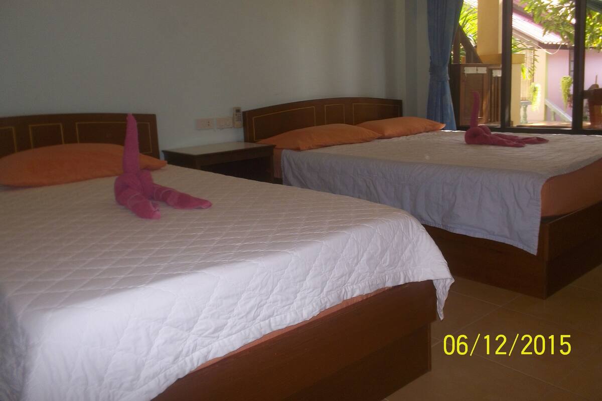 Two single beds with wooden headboards, white bedding, and orange pillows.