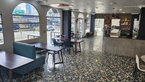 Een restaurantinterieur met een terrazzovloer, grote ramen en een bar.