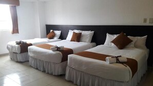 Een hotelkamer met vier eenpersoonsbedden op een rij, elk met witte beddengoed en bruine accenten.