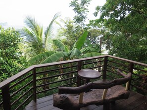A wooden deck with a railing, a round table, and a bench.