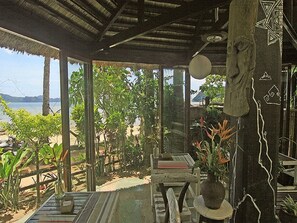 A covered outdoor seating area with a view of the beach and sea.