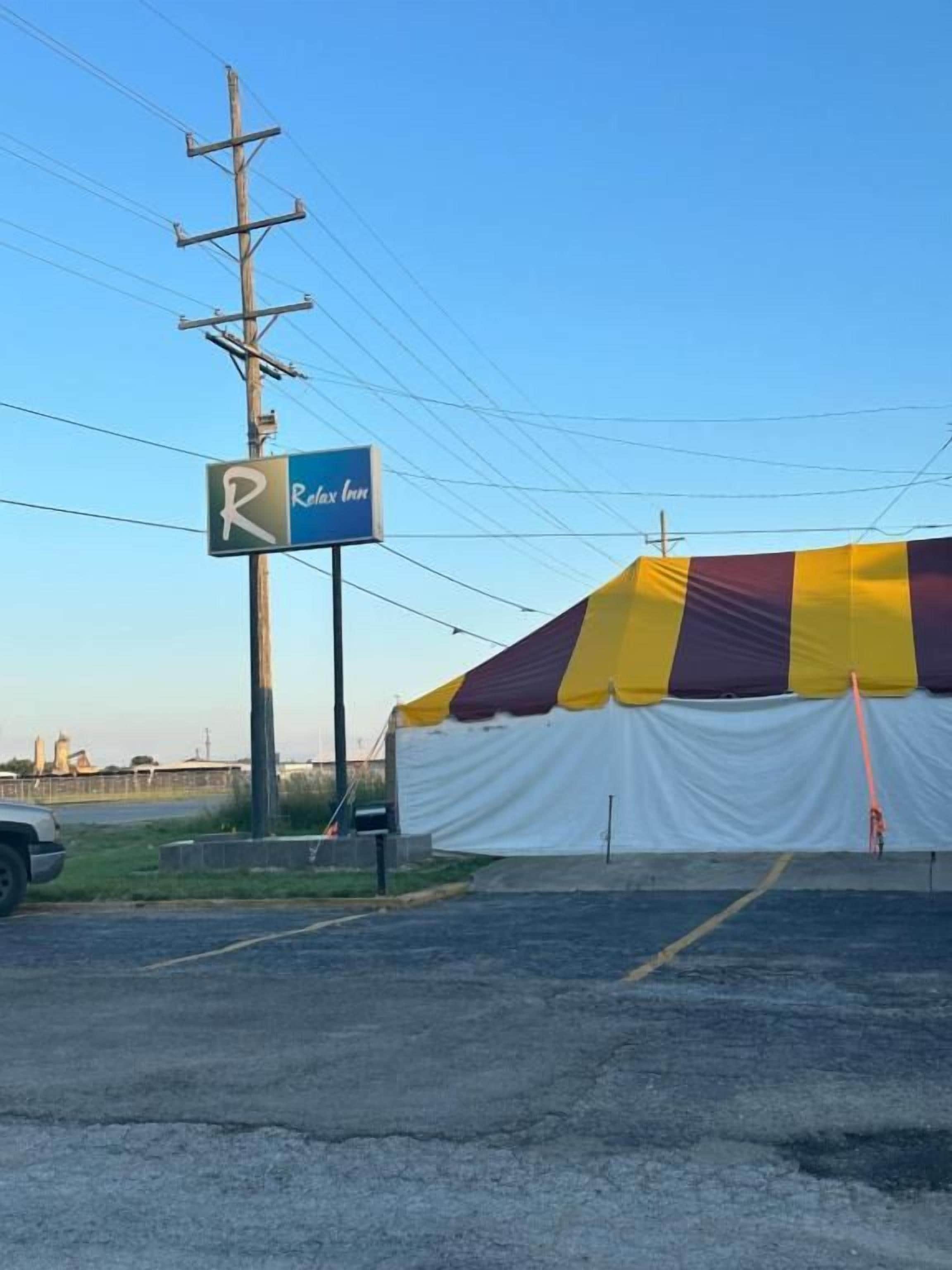 Un estacionamiento con una gran estructura tipo carpa y un letrero para un negocio llamado 'Relax Inn'.
