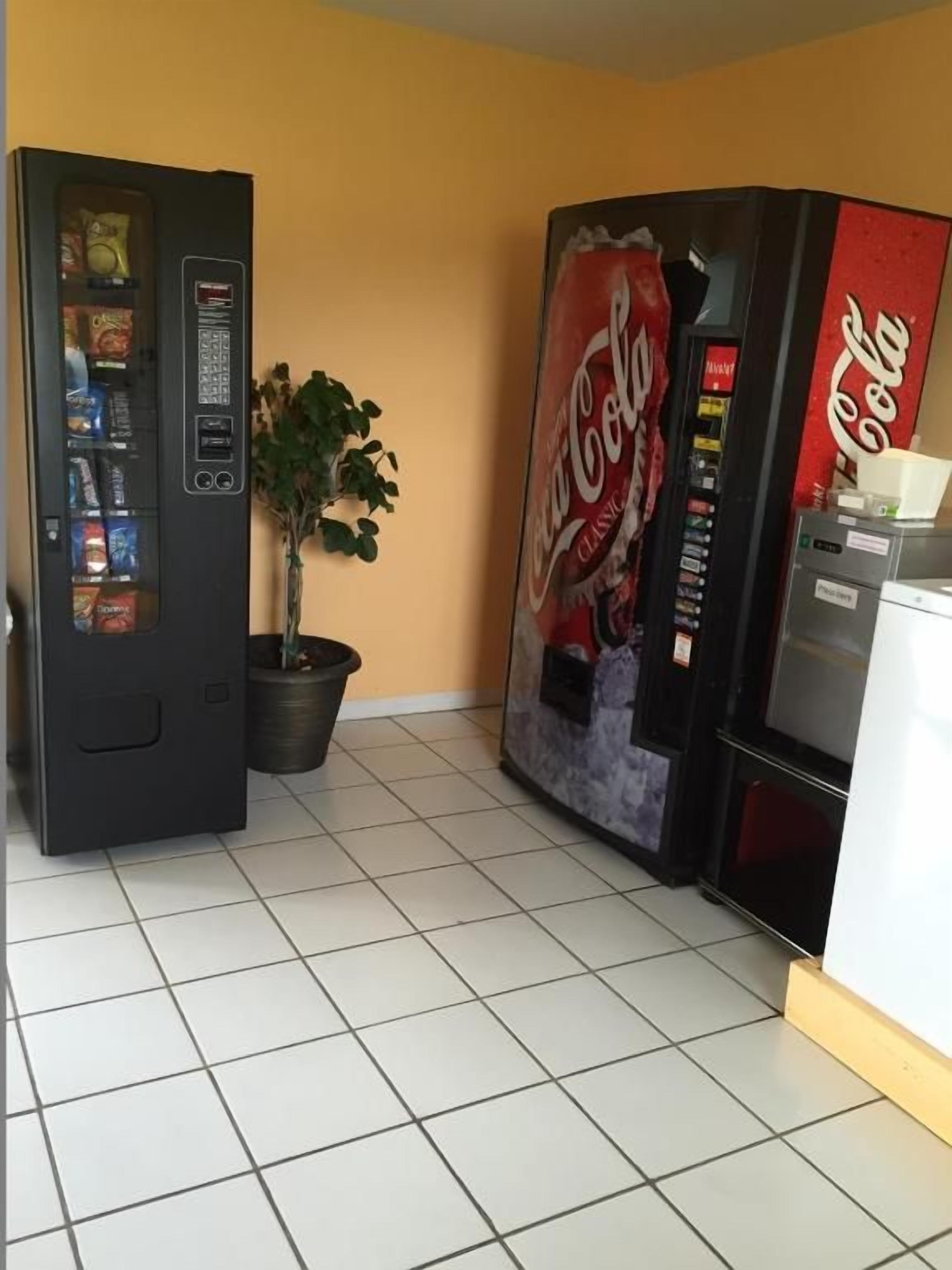 Zona de máquinas expendedoras con una máquina de Coca-Cola y otra más pequeña con diferentes aperitivos.