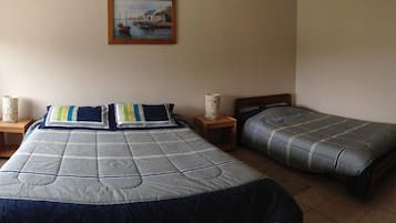 A bedroom with two single beds, a painting on the wall, and two bedside tables with lamps.