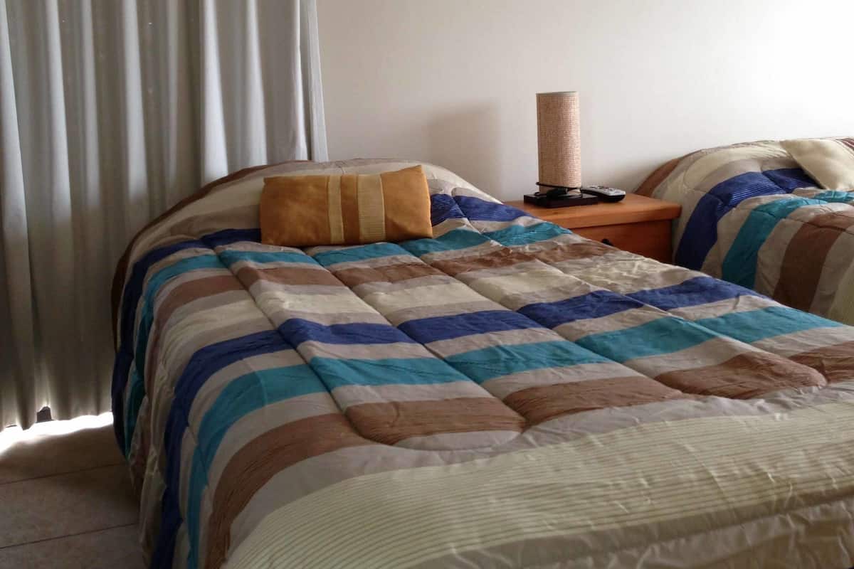 A bedroom with a bed, a nightstand, a lamp, and a painting on the wall.
