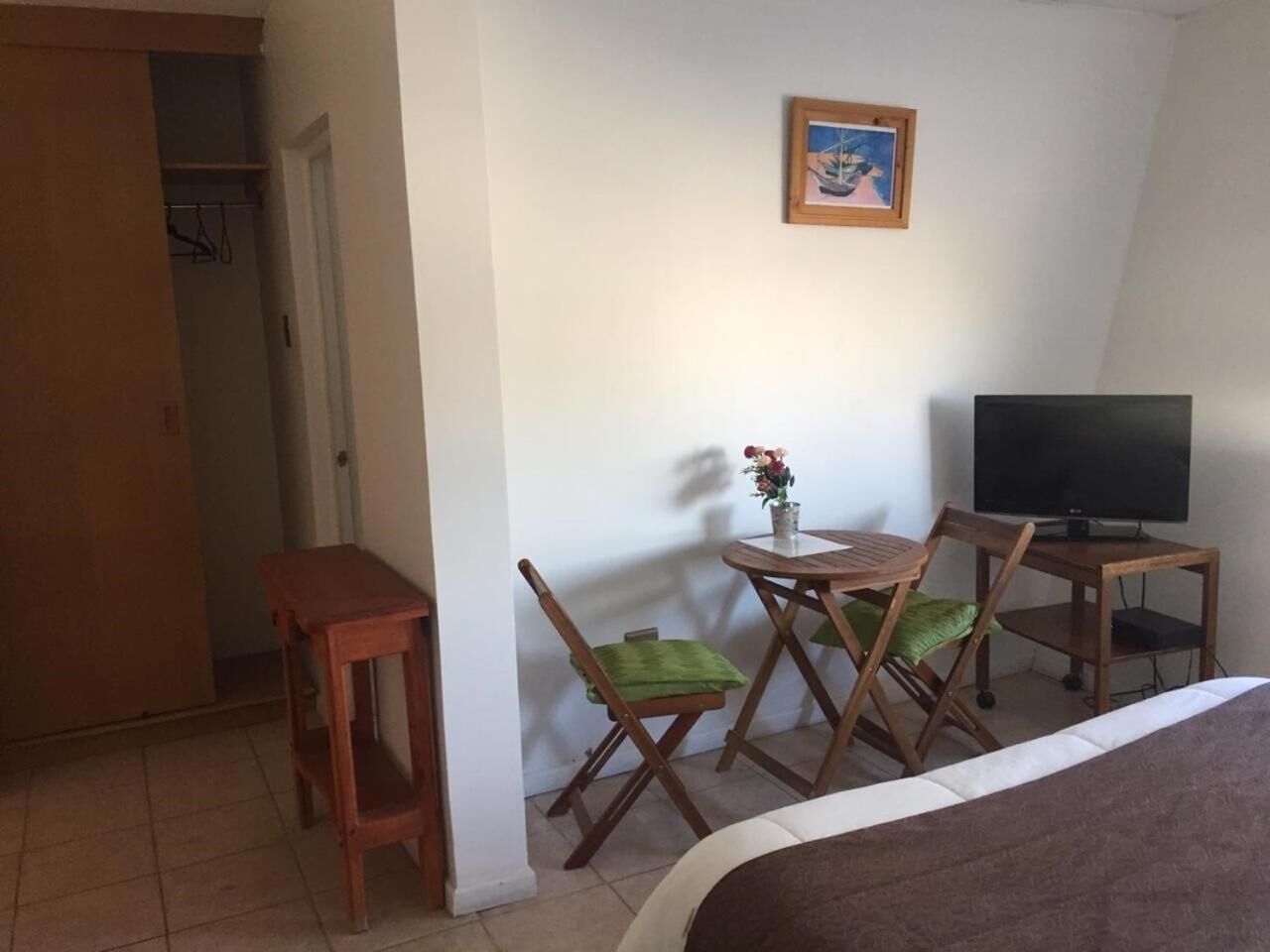 Une chambre d’hôtel comprenant un lit, une télévision, une petite table avec une chaise et une armoire.