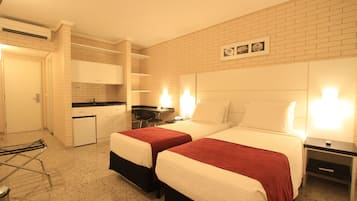 A hotel room with two beds, a kitchenette, a small table, and a chair.