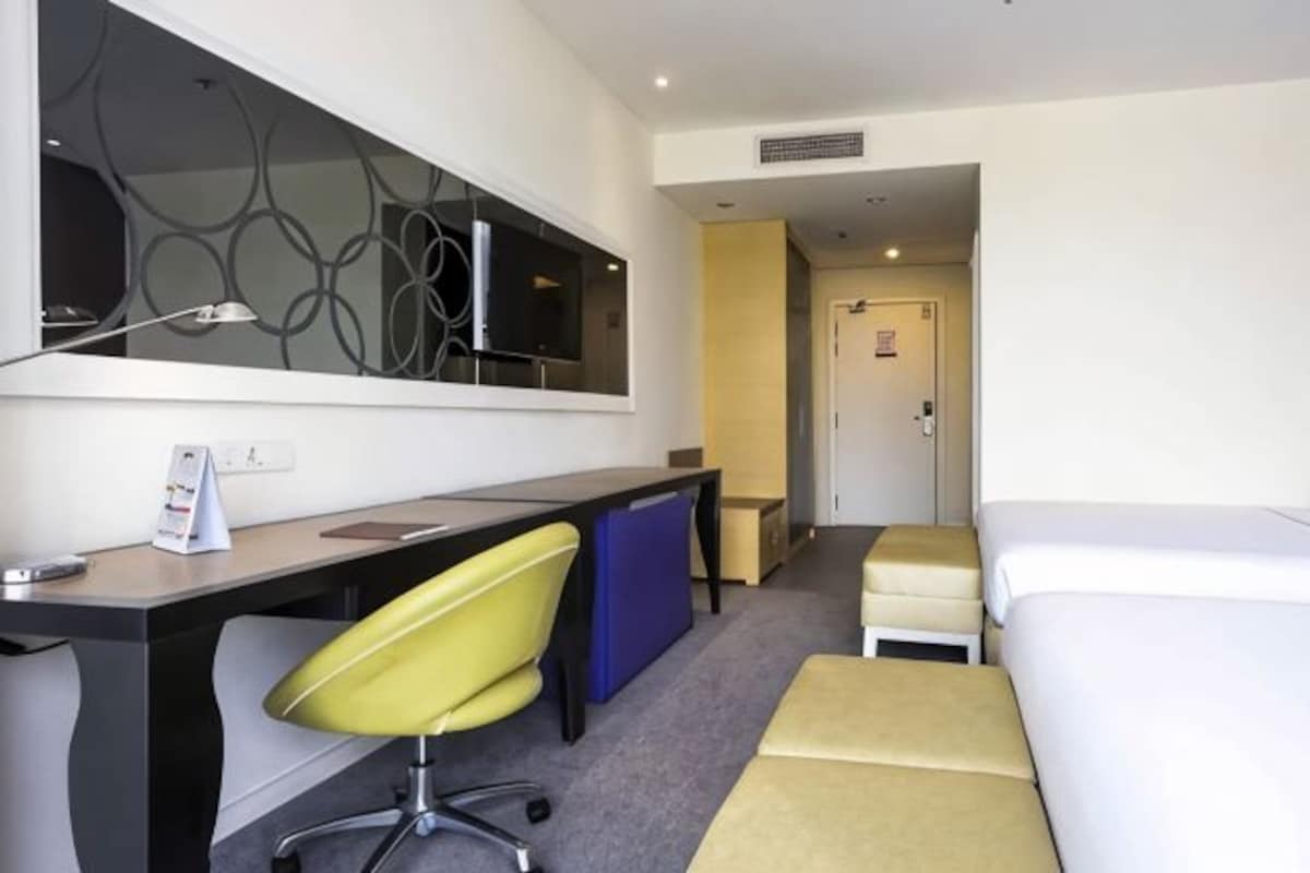 A hotel room with a desk, chair, bed, and a television.