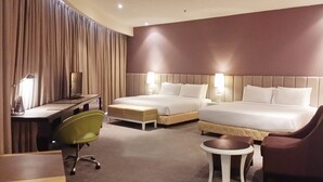 Habitación de hotel con dos camas, un escritorio, una silla, una mesita y una cortina.