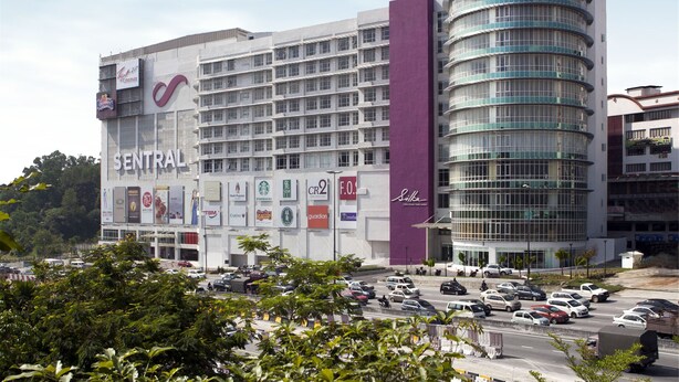 Un hotel con un edificio central y una torre de vidrio curva.