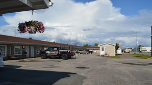 Un motel avec un parking, un pot de fleurs suspendu et une enseigne McDonald's en arrière-plan.